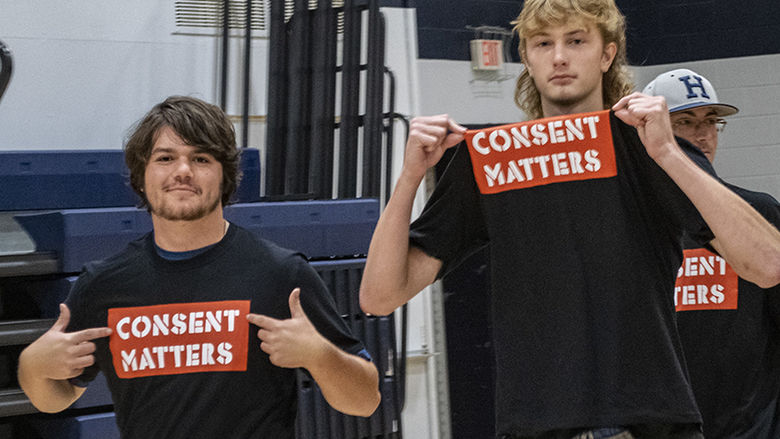 Two students wear black shirts featuring the words "Consent Matters" in a red box