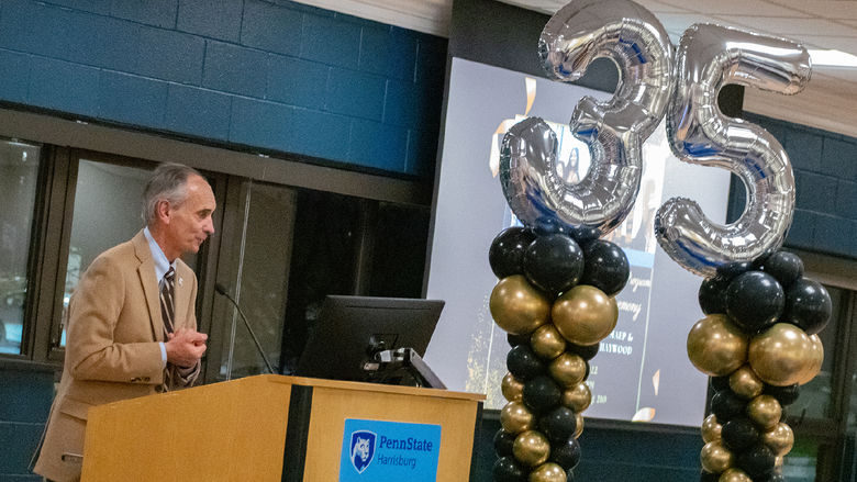 Penn State Harrisburg Chancellor John M. Mason Jr. speaks during the anniversary celebration for the Multicultural Academic Excellence Program. Large balloons shaped like the number 35 are in the background.