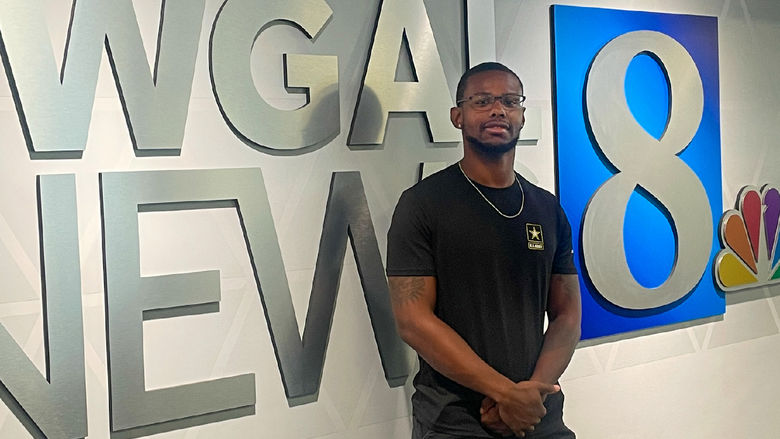Ashon Calhoun stands in front of a wall with WGAL News 8 logo