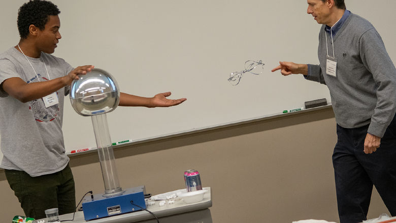 A student and professor do an experiment with an electrostatic generator