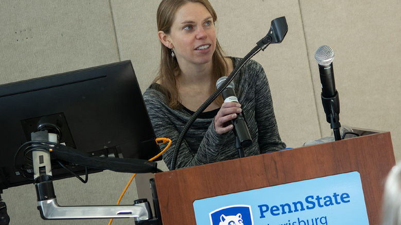 A woman speaks from behind a lectern, which has a Penn State Harrisburg logo on it