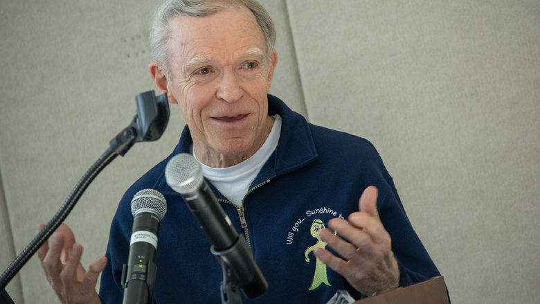 A man speaks at a podium from behind microphones