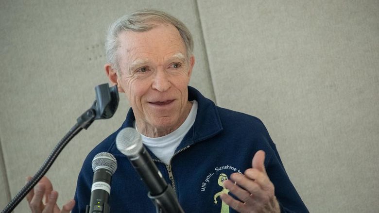 A man speaks at a podium from behind microphones