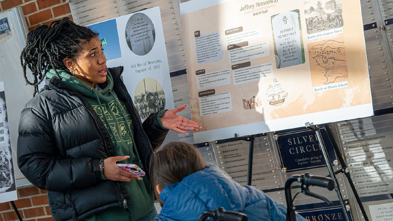 A student explains her research poster to another student