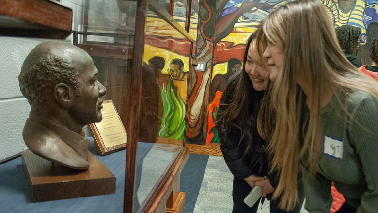 Students look at a bust of Oliver LaGrone in a case