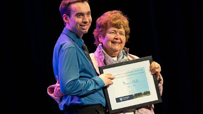 Daniel Mills and Linda Rhen pose holding a framed award certificate 