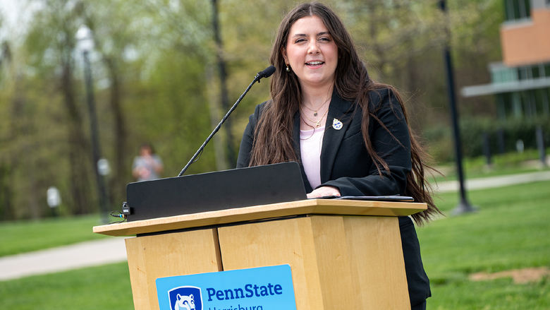 A woman speaks from a lectern outdoors
