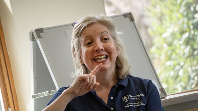 Heidi Haas points to her lips as she demonstrates how to make a sound