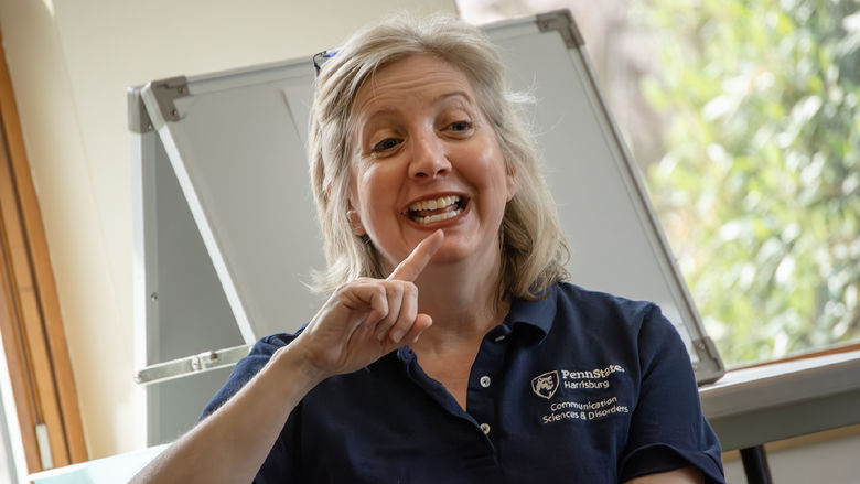 Heidi Haas points to her lips as she demonstrates how to make a sound
