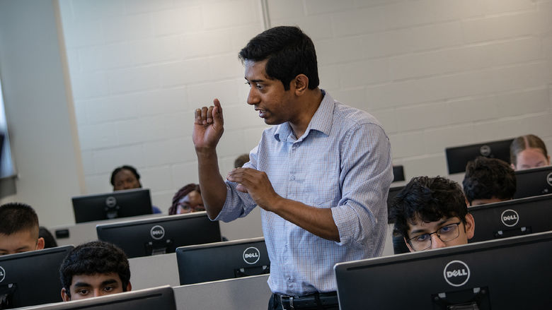 A professor instructs students sitting at computers