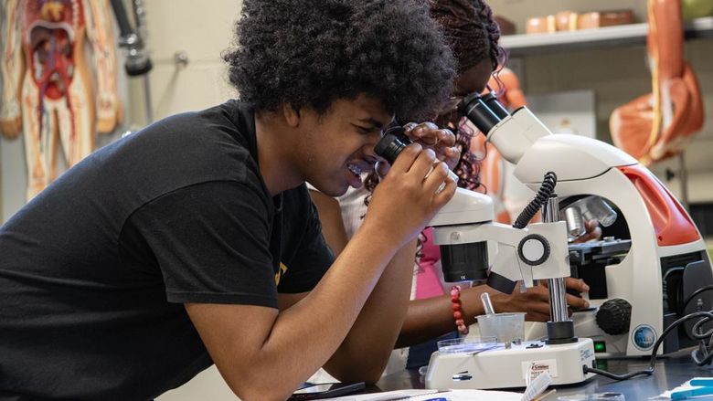 High schools students peer into microscopes