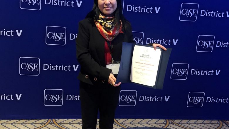 A woman holds an award in front of a CASE District V background