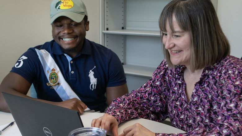 A faculty member and a student look at a laptop