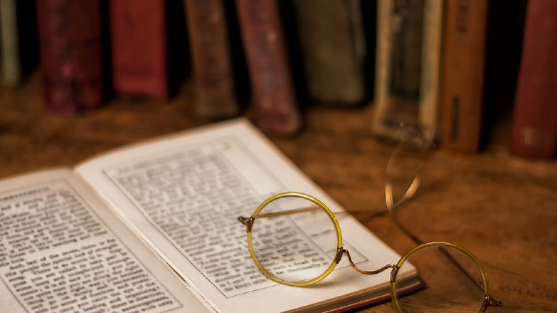cirlcle frame eye glasses sitting atop an open book