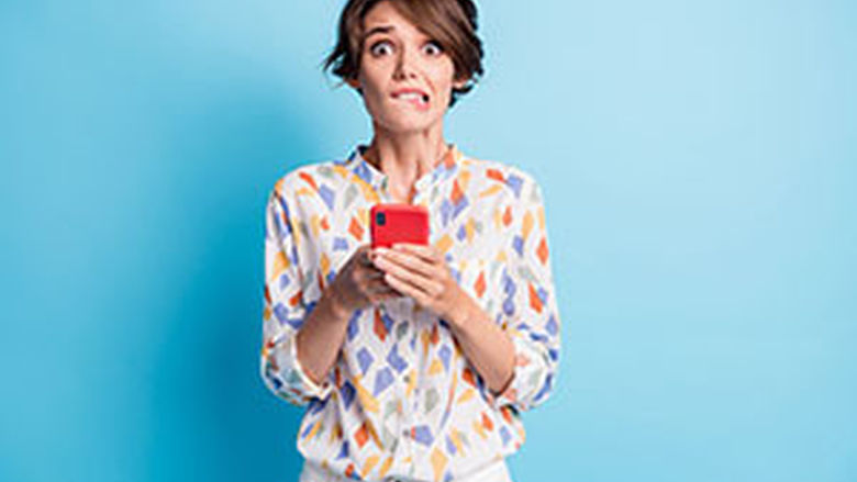 Anxious young woman with her mobile phone biting her lips