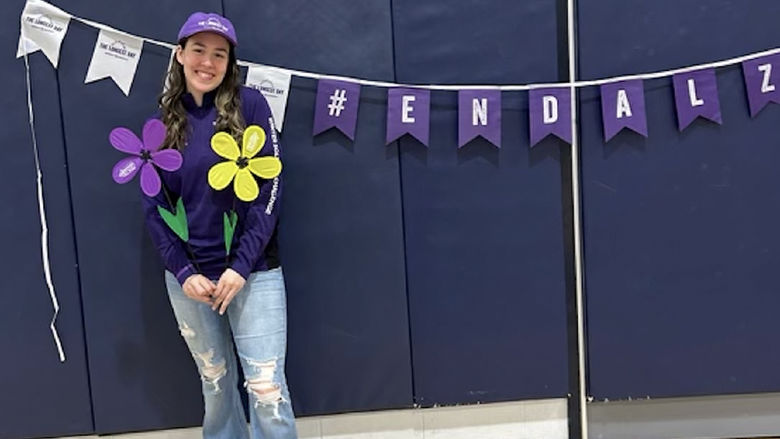 Carolina Hernandez stands next to a purple banner that says #endalz