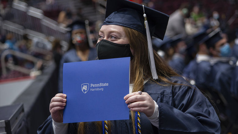 New Penn State Harrisburg graduate holds up diploma at Commencement ceremony