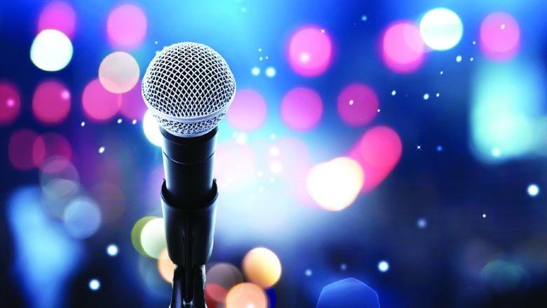 Image of microphone on stand with stage lights in the distance