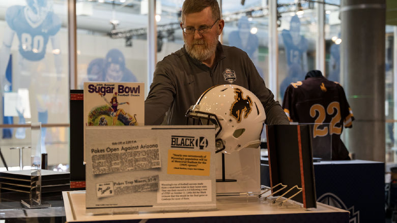 Denis Crawford adjusts an exhibit at the College Football Hall of Fame