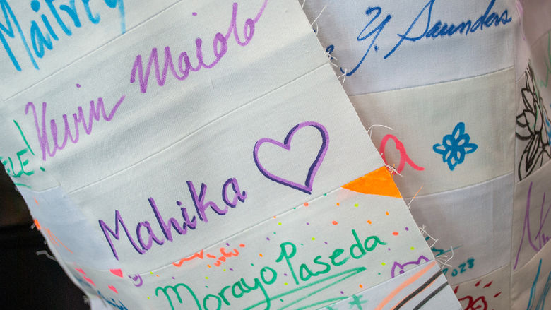 A closeup of Emily Pettet's signature coat in progress - white cloth squares with signatures in bright colors