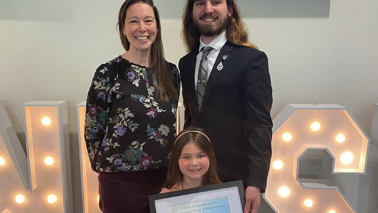 Fabian Vantassell poses with a professor and his little sister, who holds an award he received