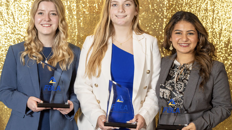 Three women hold FBLA trophies