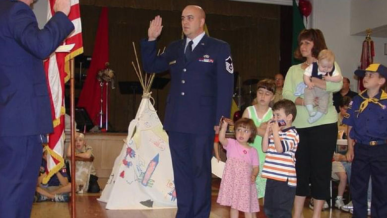 Gary Barb raises his right hand during his final reenlistment ceremony, surrounded by family