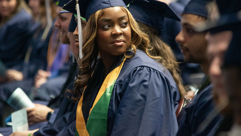 A graduate looks into the crowd during commencement