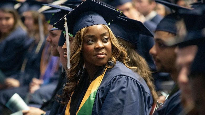 A graduate looks into the crowd during commencement