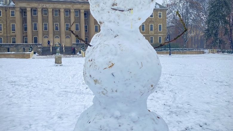 A snowman with Old Main in the background