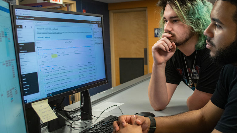 Two students look at a computer screen while working on the ITS Service Desk.