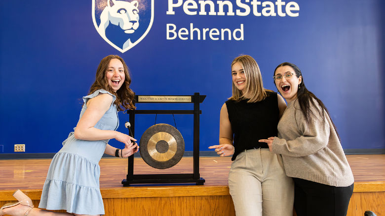 A group of Scholars stand in front of the gong at PSU Behrend