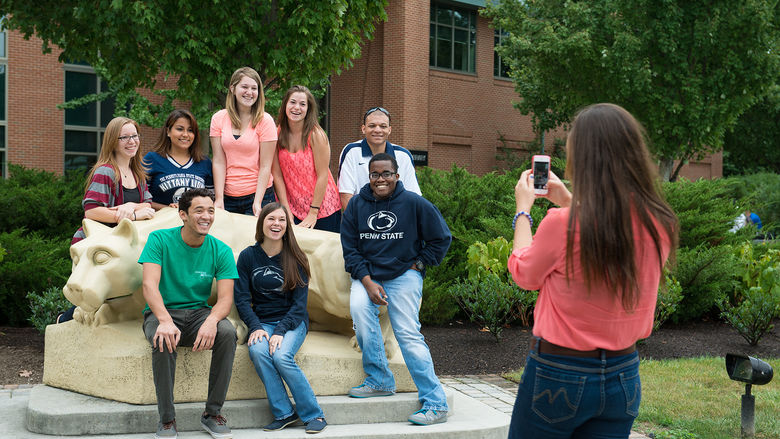 students pose for a photo in front of Penn State Harrisburg's Lion Shrine and Library