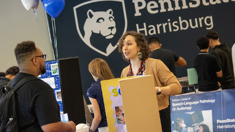 A student talks with a faculty member at a table during Majors Fest