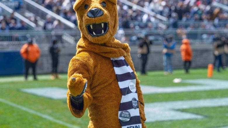 The Nittany Lion points to the camera while standing on the football field