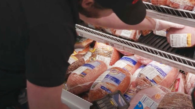 man filling meat case at grocery store