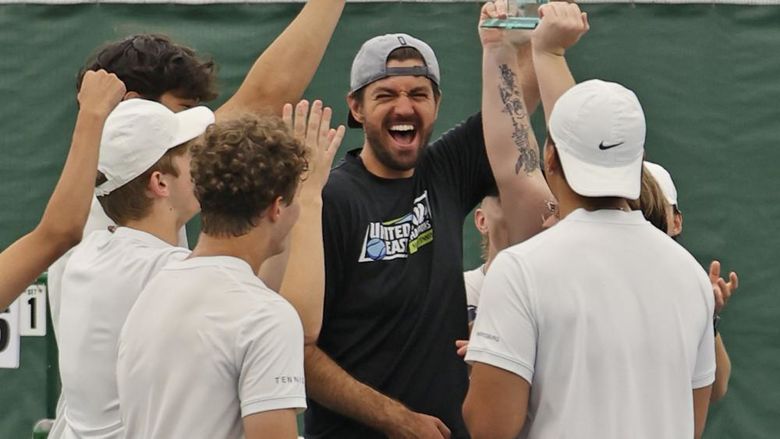 A group of men hold a trophy in the air and celebrate