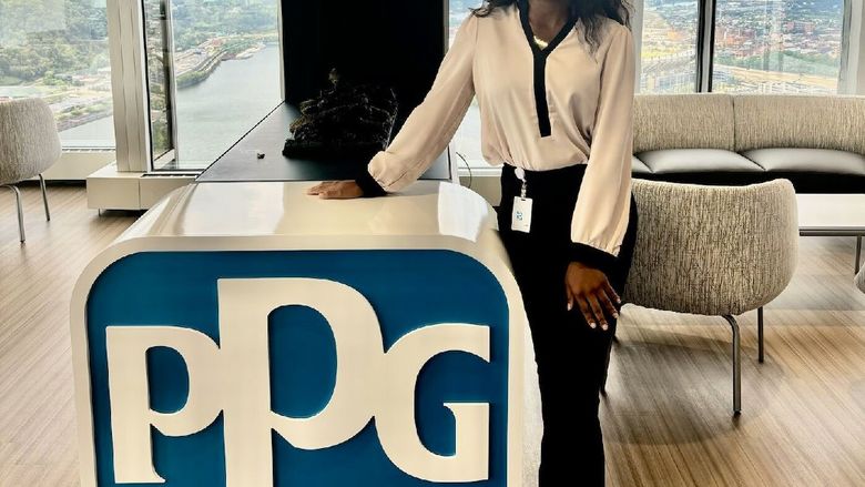 A student stands next to a PPG sign