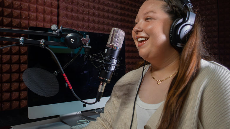 A student speaks into a microphone in a podcast studio