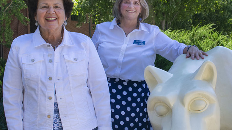 Linda Rhen and Sandy McBride pose with the Lion statue