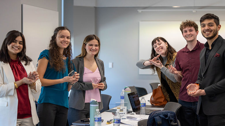 Six students from the winning Policy Simulation Competition team hold up their awards