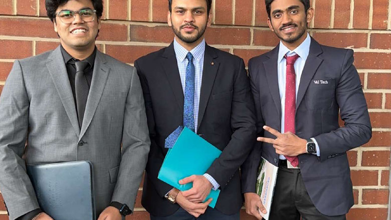 Purav and two friends all in suits holding folders