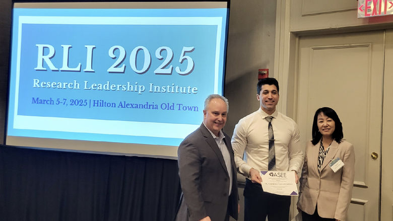 Photo of Fariborz Tavangarian holding an award, standing with two people, near a screen that says RLI 2025