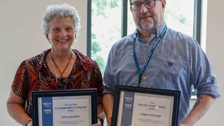 Toni Chainey and Chris Weaver pose holding framed awards