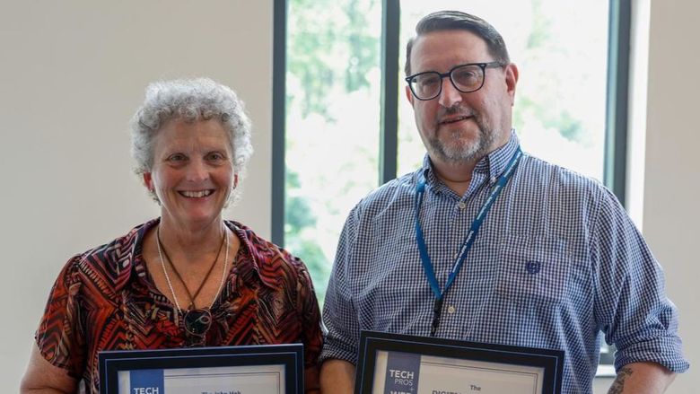 Toni Chainey and Chris Weaver pose holding framed awards