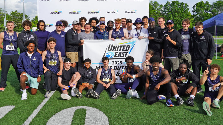 Track and field athletes gather around a championship banner