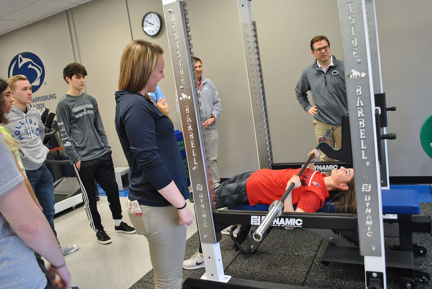 several people watching male on weight bench