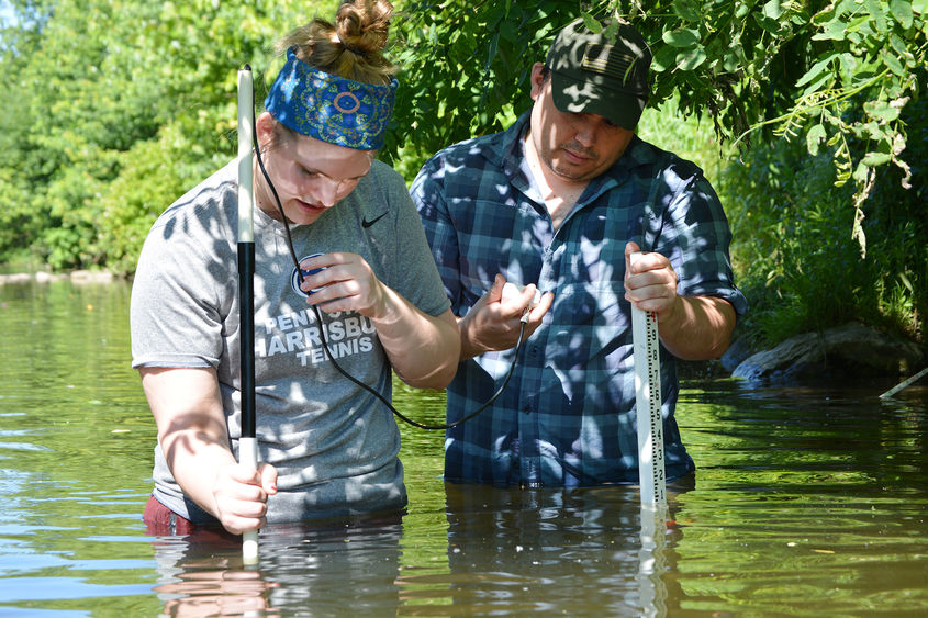 male and female students testing stream water