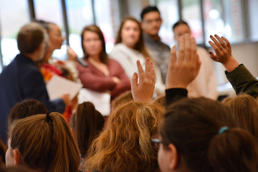 upraised hands at town hall meeting