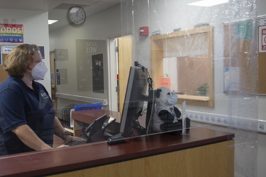 woman behind plastic barrier at desk